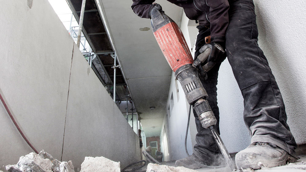 Mann mit Presslufthammer zerkleinert Betonplatten