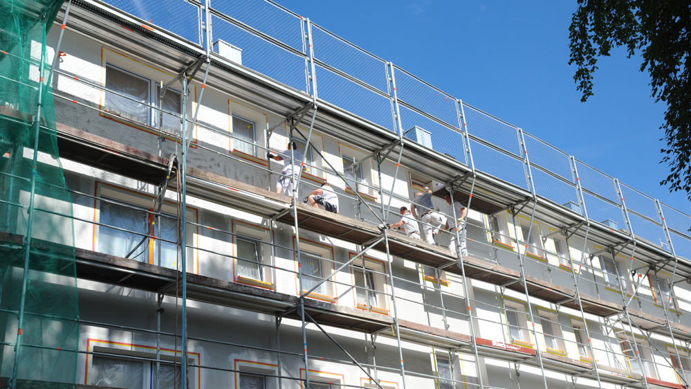 Arbeiter auf einem Baugerüst beim Sanieren einer Hausfassade